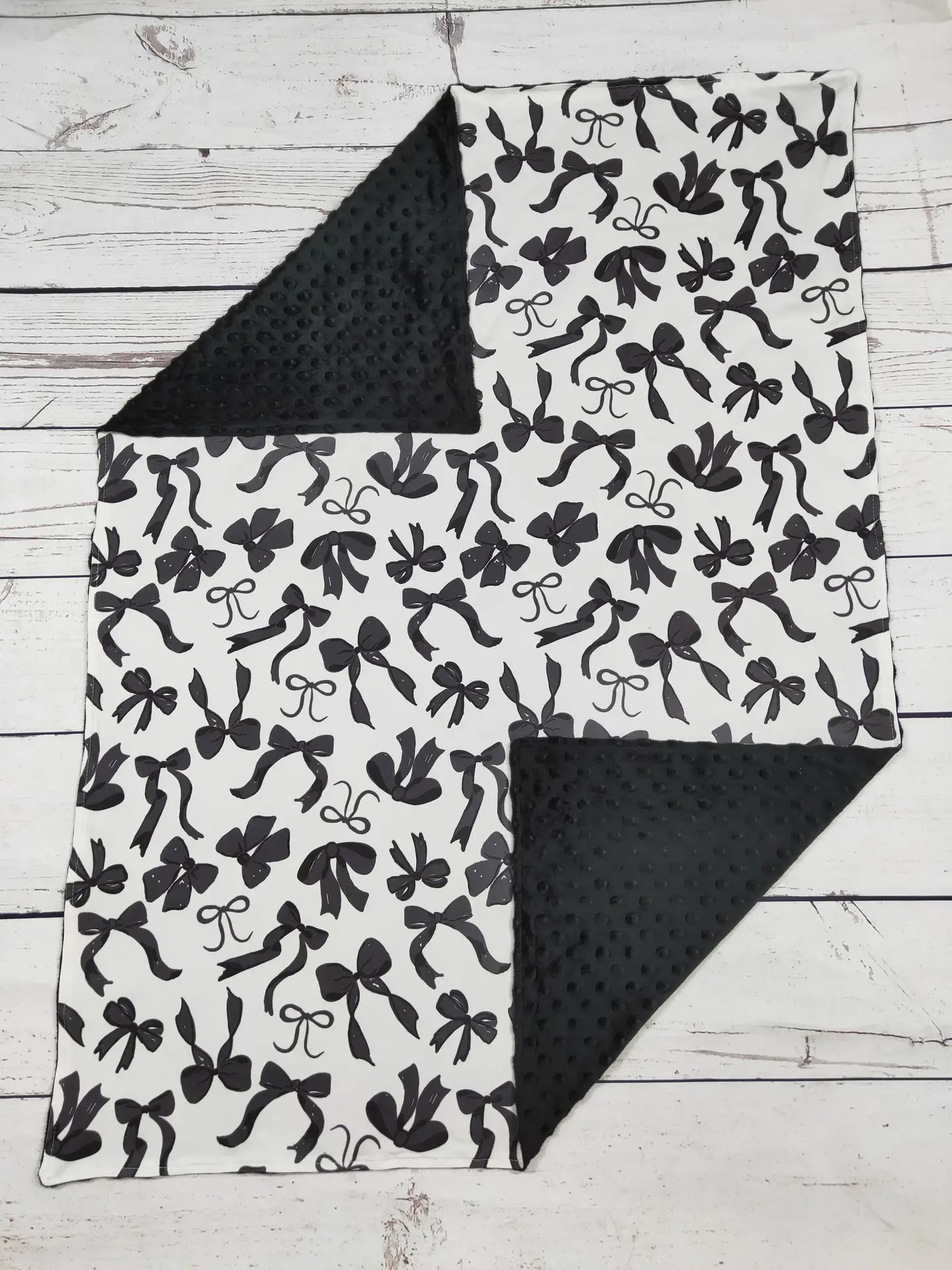 Black and white bow print baby blanket with black minky dot backing