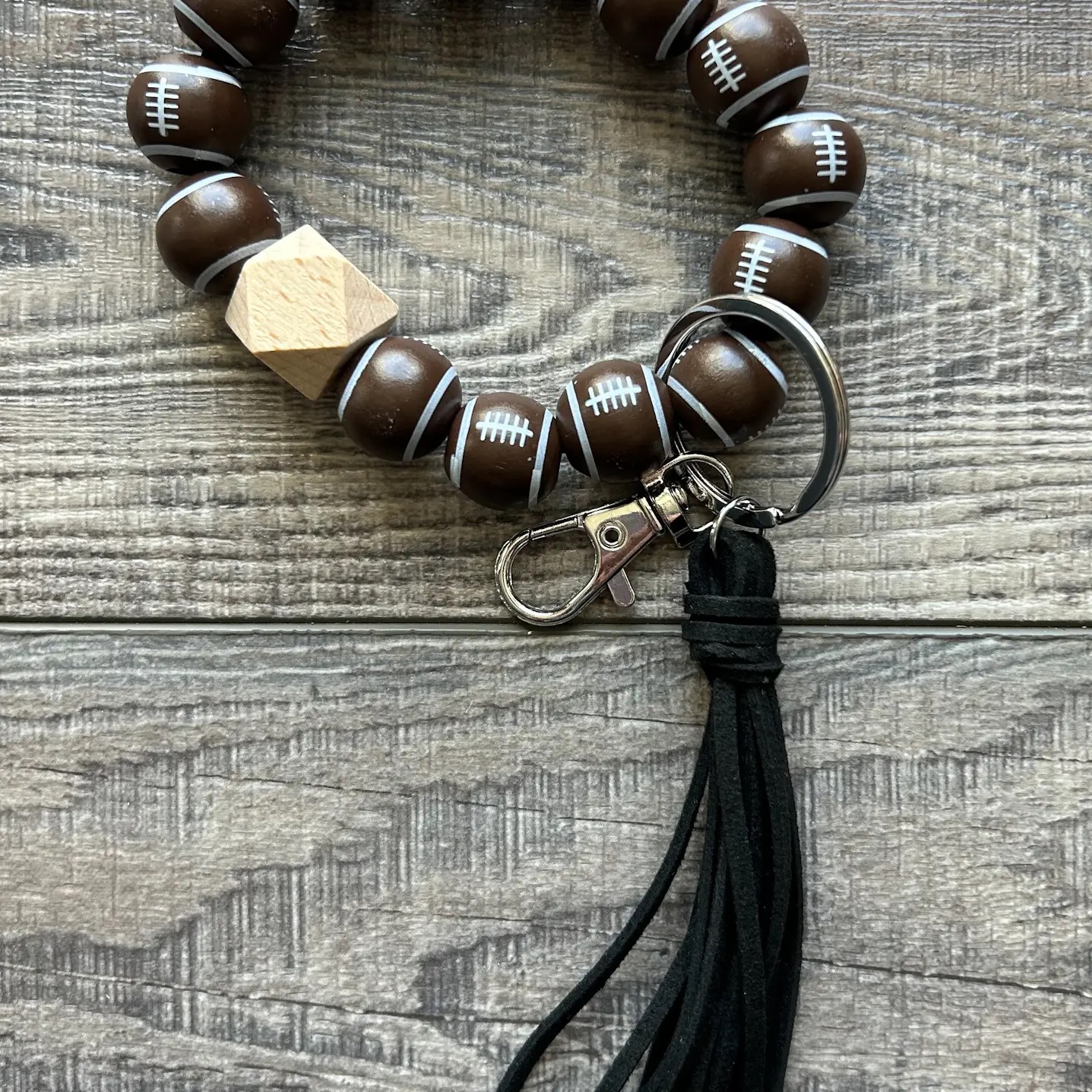 Football-themed silicone bead wristlet keychain with wood accent and black tassel