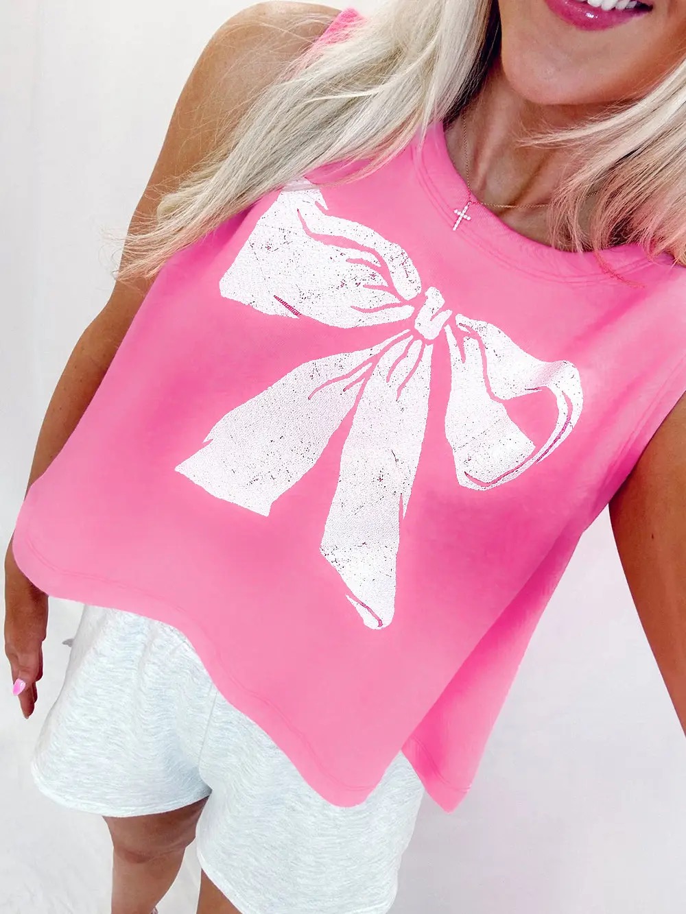 Pink sleeveless graphic tank top with large white distressed bow print