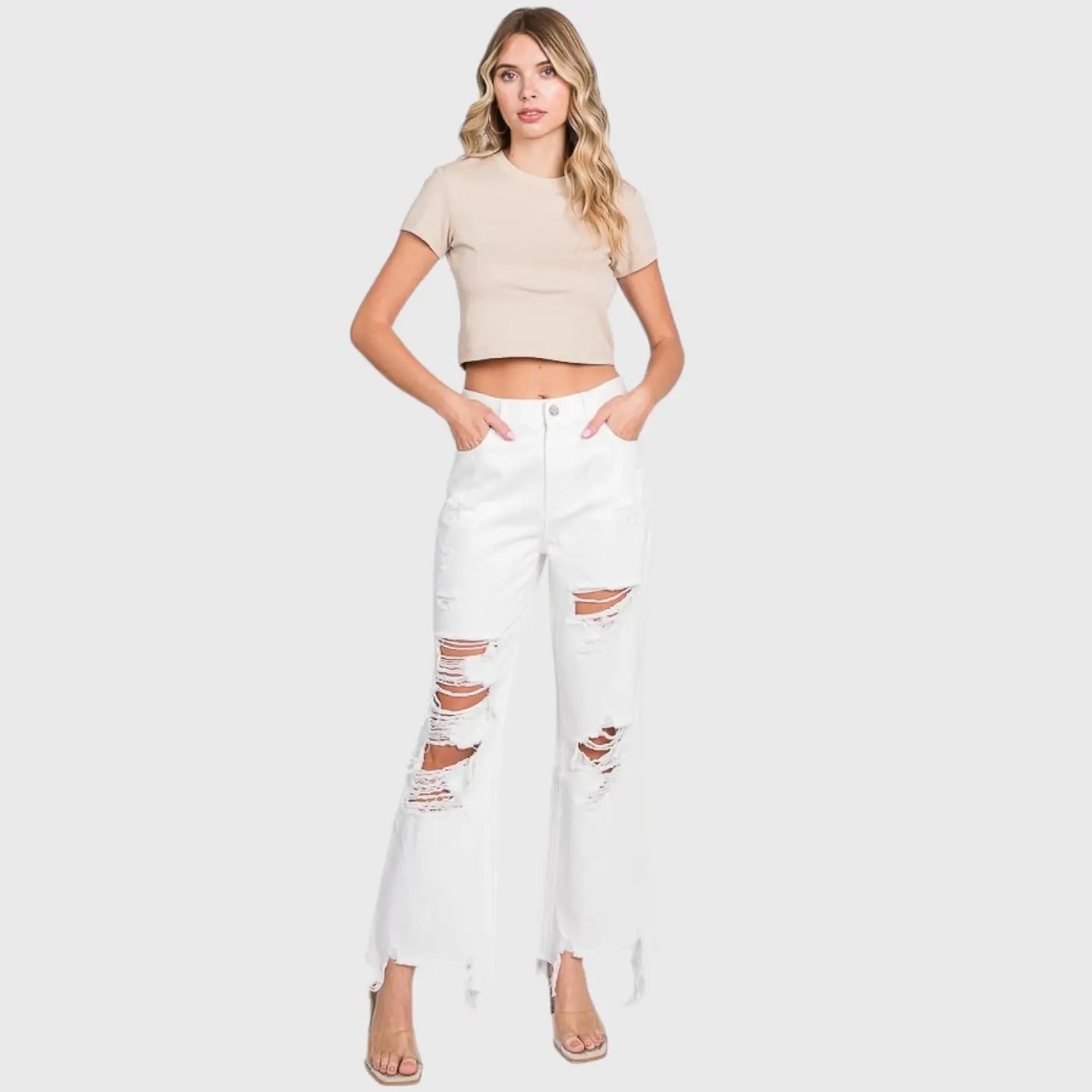 White distressed wide-leg jeans with heavy ripped detailing paired with a beige crop top